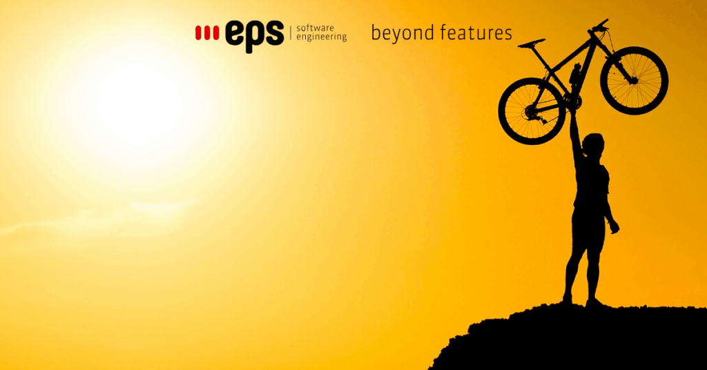 Silhouette of a biker holding their bike in the air against a sunset sky during the Bike to Work campaign.